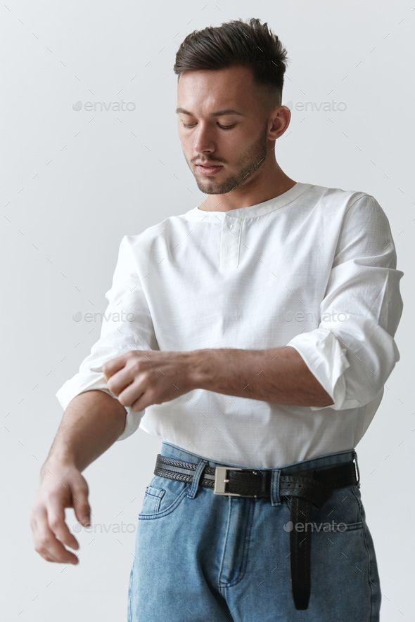 Handsome attractive serious model man guy wear linen shirt rolling up sleeves posing isolated on