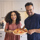 Couple At Home With Man With Down Syndrome And Woman Holding Homemade Pizza In Kitchen Together - PhotoDune Item for Sale