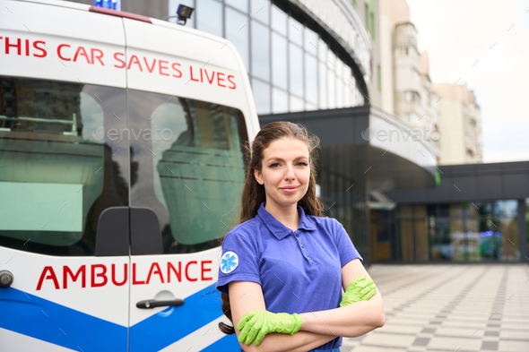 Female medic stands on the street near an ambulance