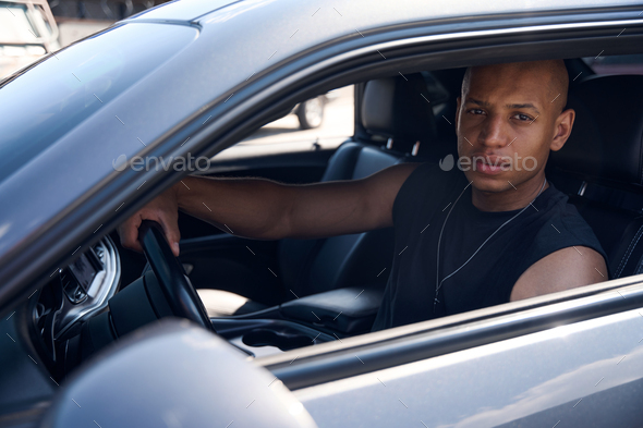 Serious African American man sitting on driver seat of his car
