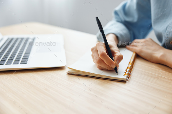 Closeup shot of woman\'s hand writing to do list future plans for work week on the table in office