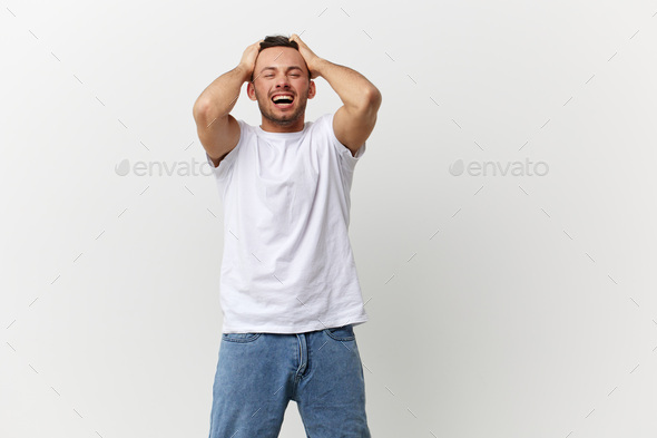Overjoyed screaming angry tanned handsome man in basic t-shirt tearing his hair out posing isolated