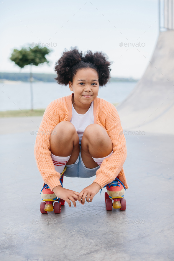 African American young girl roller skating outdoors, child playing on