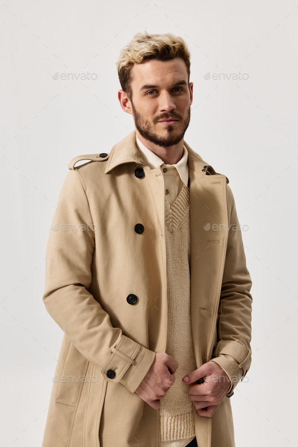 portrait of a blonde in a beige coat and a light background beautiful face trend of the season