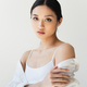 Young asian woman in white clothes touching arm isolated on grey - PhotoDune Item for Sale
