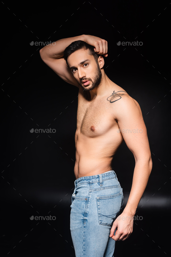 Shirtless man in jeans posing on black background Stock Photo by
