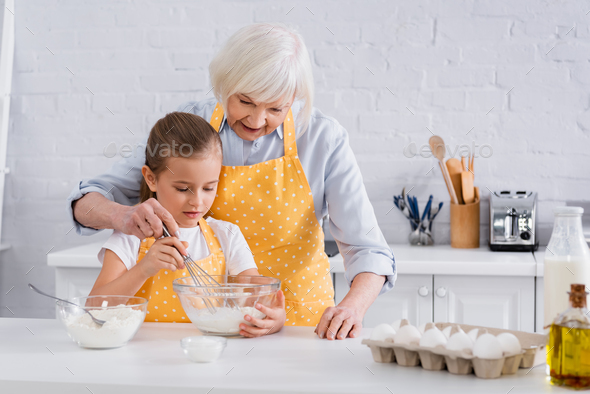 Granny and kid cooking together near ingredients in kitchen Stock Photo ...