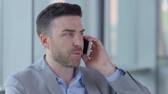 Young businessman using cell phone in office lobby