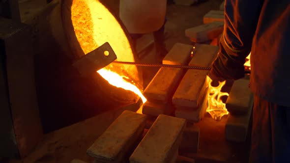 Male worker pouring molten metal in mold at workshop 4k alt
