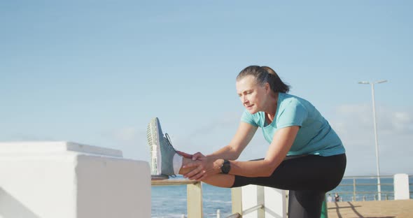 Senior woman stretching her legs on a promenade alt
