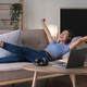 Woman listening music in headphones while lying on sofa in room - PhotoDune Item for Sale