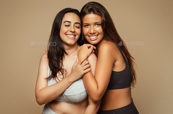 Smiling millennial diverse women hugs in underwear enjoy health, beauty care  isolated on beige Stock Photo by Prostock-studio