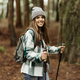Smiling pretty young caucasian lady in jacket, hat with trekking sticks walk at weekend, enjoy - PhotoDune Item for Sale