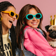 Two joyful young women in trendy glasses carrying cute pug dog and smiling against pink background - PhotoDune Item for Sale