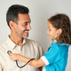 little girl dressed as a nurse playing doctor with her father on neutral background - PhotoDune Item for Sale