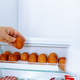 Closeup human hands put chicken eggs in egg-laying compartment in refrigerator - PhotoDune Item for Sale