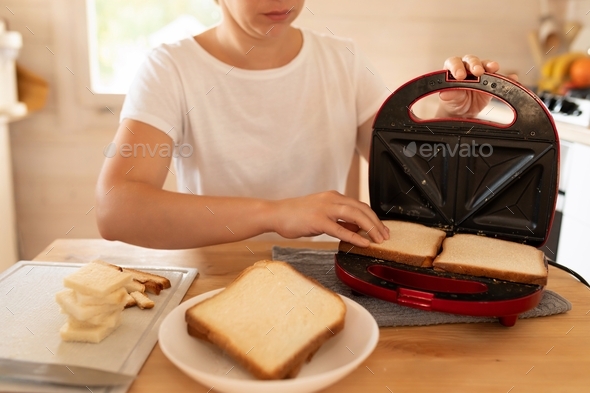 a woman toasting bread in a toaster oven in her kitchen