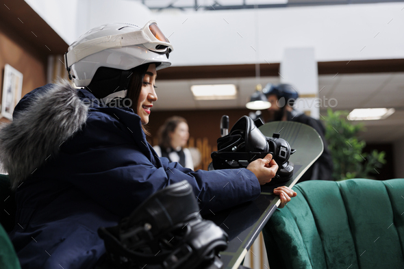 Asian woman checking snowboard gear