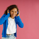 Pretty woman touching headphones while looking at camera on pink studio background - PhotoDune Item for Sale