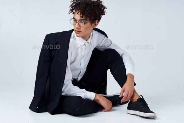 handsome guy in a jacket and shirt and glasses In a bright room photo studio model hairstyle curly