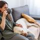 Woman drinking coffee and relaxing at home with her pet dog - PhotoDune Item for Sale