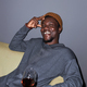Smiling young Black man with red wine sitting on couch smiling at camera - PhotoDune Item for Sale