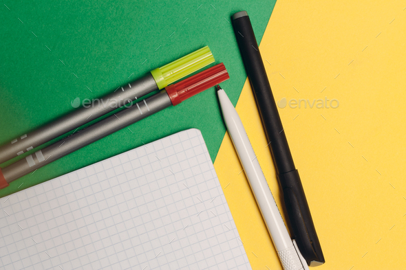 colored pens and markers on a bright background and a white notepad on the table