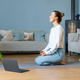 Young woman meditating at home with an online video meditation lesson using a laptop. Copy space. - PhotoDune Item for Sale