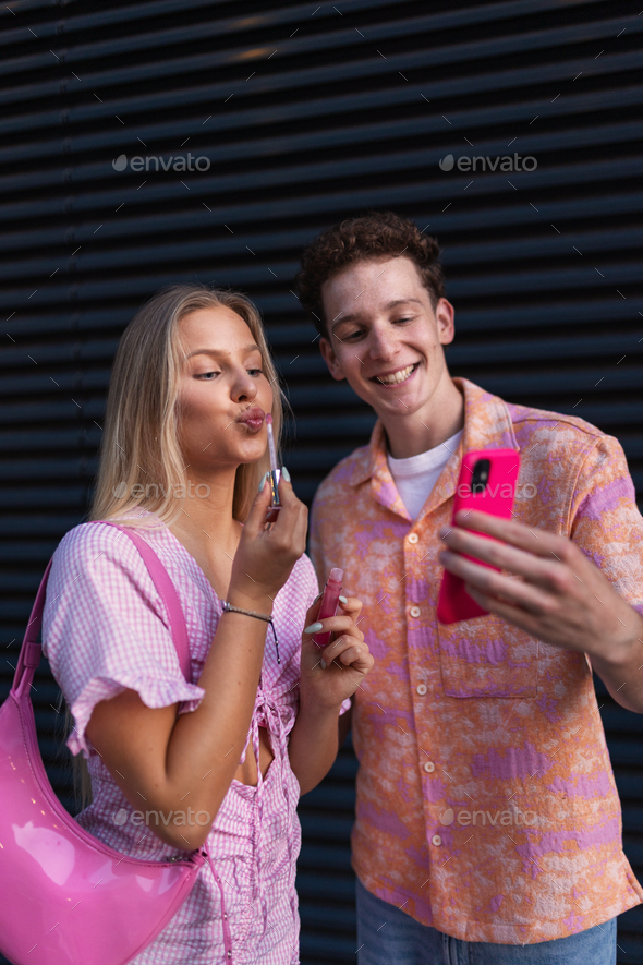 Gen Z couple in pink outfit taking selfie before going the cinema to watch movie.