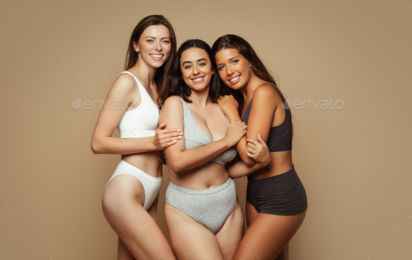 Glad millennial pretty diverse women in underwear with different body types  hugs, enjoy beauty care Stock Photo by Prostock-studio
