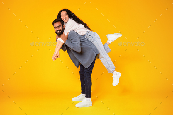 Cheerful woman holding on to boyfriends head while having piggyback ride  stock photo