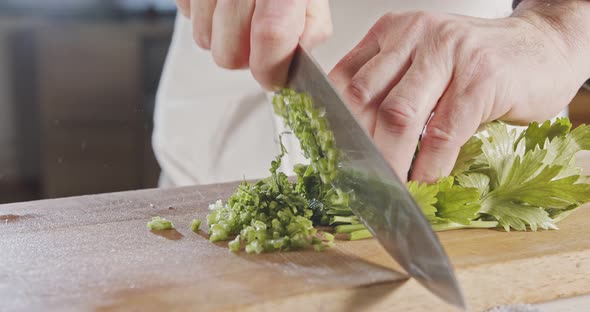 Slow motion of chef knife slicing celery leaves alt
