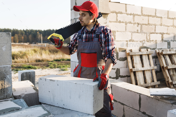 Bricklayer man is sawing autoclaved concrete blocks