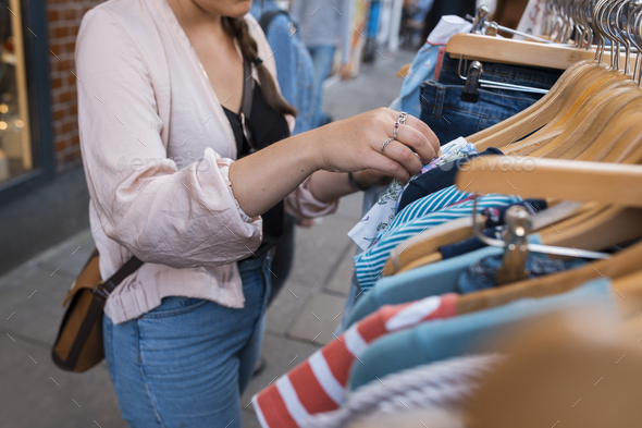 Mid section of woman browsing clothes on rack outdoors