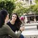 Two young women sitting in town square and talking - PhotoDune Item for Sale