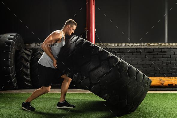 Strong sportsman doing a tire flip exercise Stock Photo by BLACKDAY