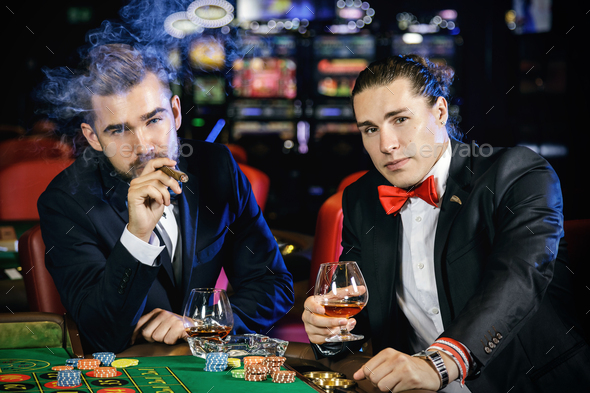 Handsome guys drinking cognac and playing roulette in the casino