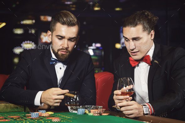 Handsome guys drinking cognac and playing roulette in the casino