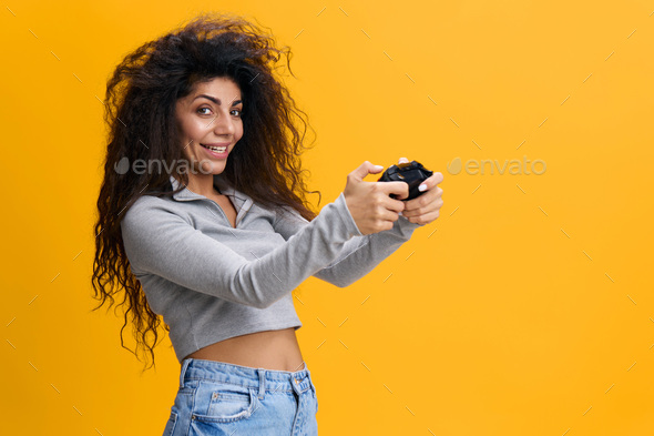Young woman of African American ethnicity 20s wear casual shirt look at camera, hold in hand play pc