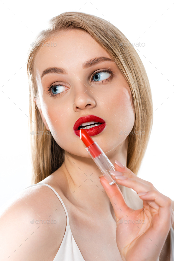 blonde young woman with red lips and blue eyes holding lipstick tube isolated on white