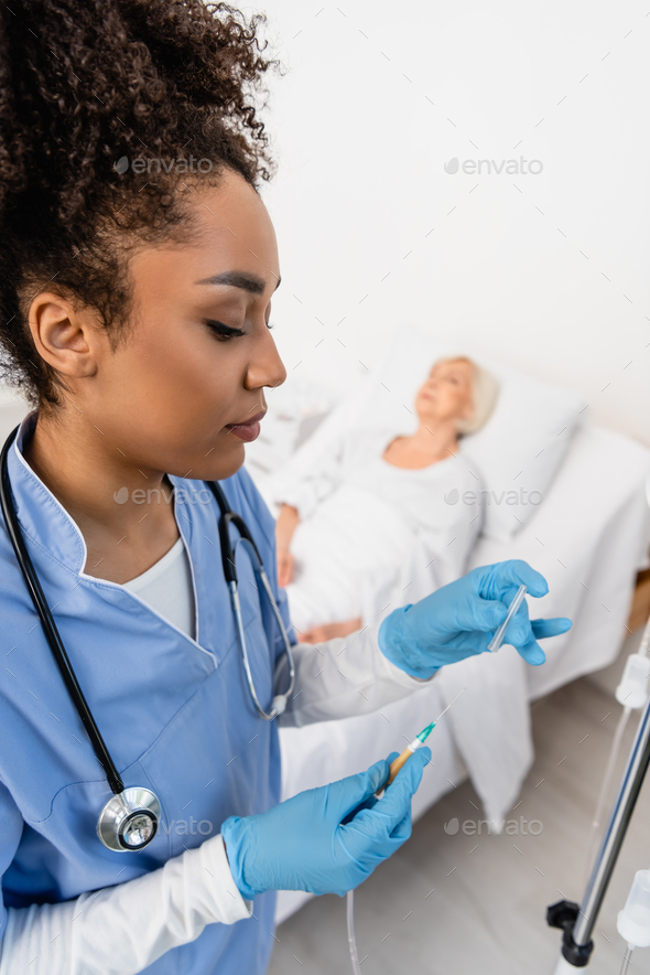 African american nurse in latex gloves holding catheter near intravenous therapy station in hospital