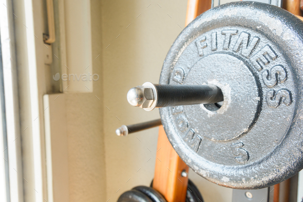Close-up of iron dumbbell that says fitness placed on exercise machine, copy space.