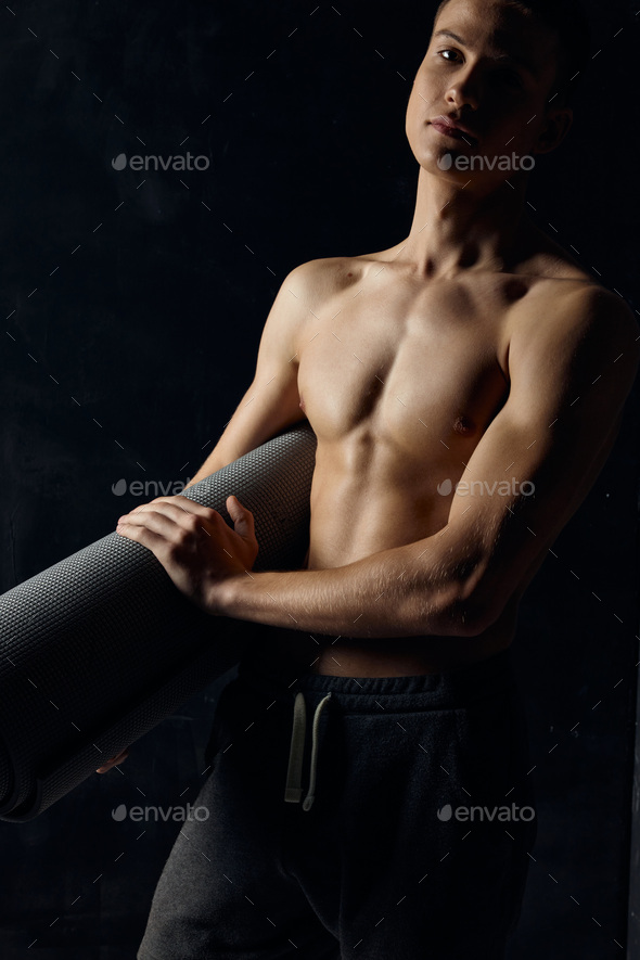 athlete in pants nude torso fitness mat black background