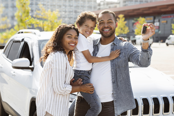 Happy black family posing next to new car, showing key Stock Photo