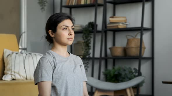Young Asian Woman Sitting On The Floor Looking Away With A Thoughtful Look, Is in A Cozy Room alt