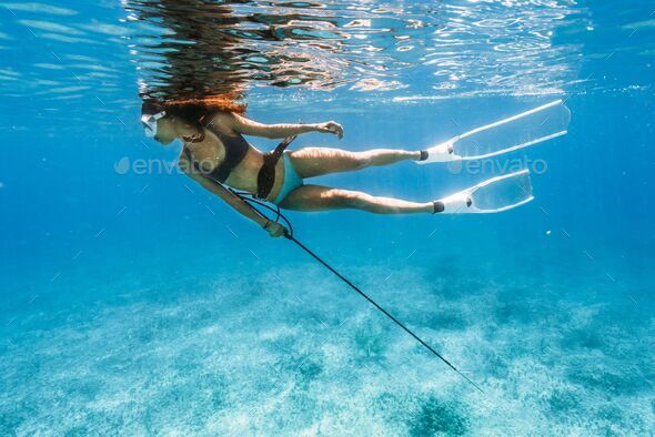 Female spearfishing under the water in the Bahamas Stock Photo by