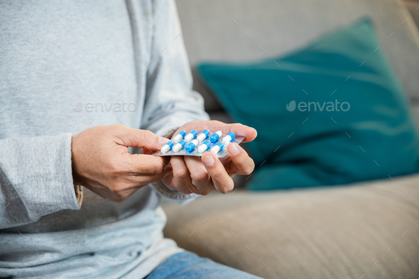 Asian worried senior man with medicine pills he read on see how to take pills before taking