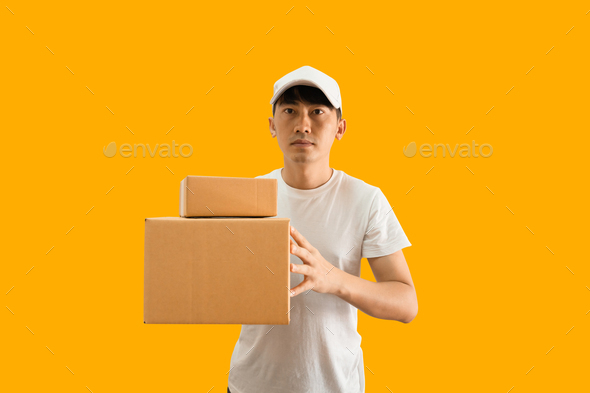 Young Asian delivery man wearing cap and white blank t-shirt holding parcel post box isolated