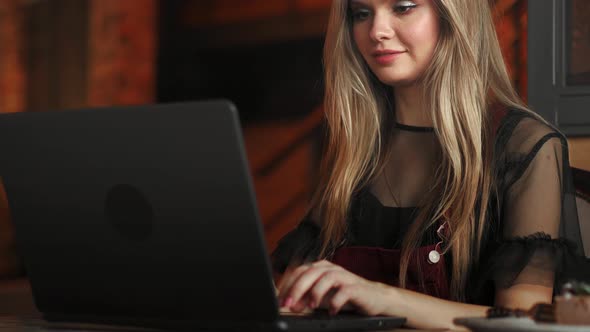 Beautiful Woman Working on Her Laptop on a Stylish Urban Restaurant alt