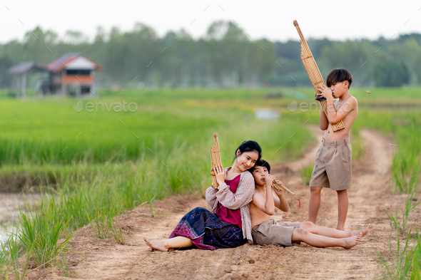 Asian woman look like older sister with traditional cloth sit close to young boy with one stand